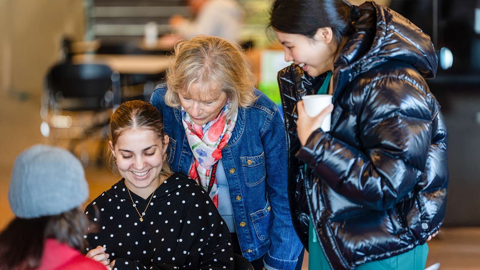 Two students smiling and a teacher behinds watching