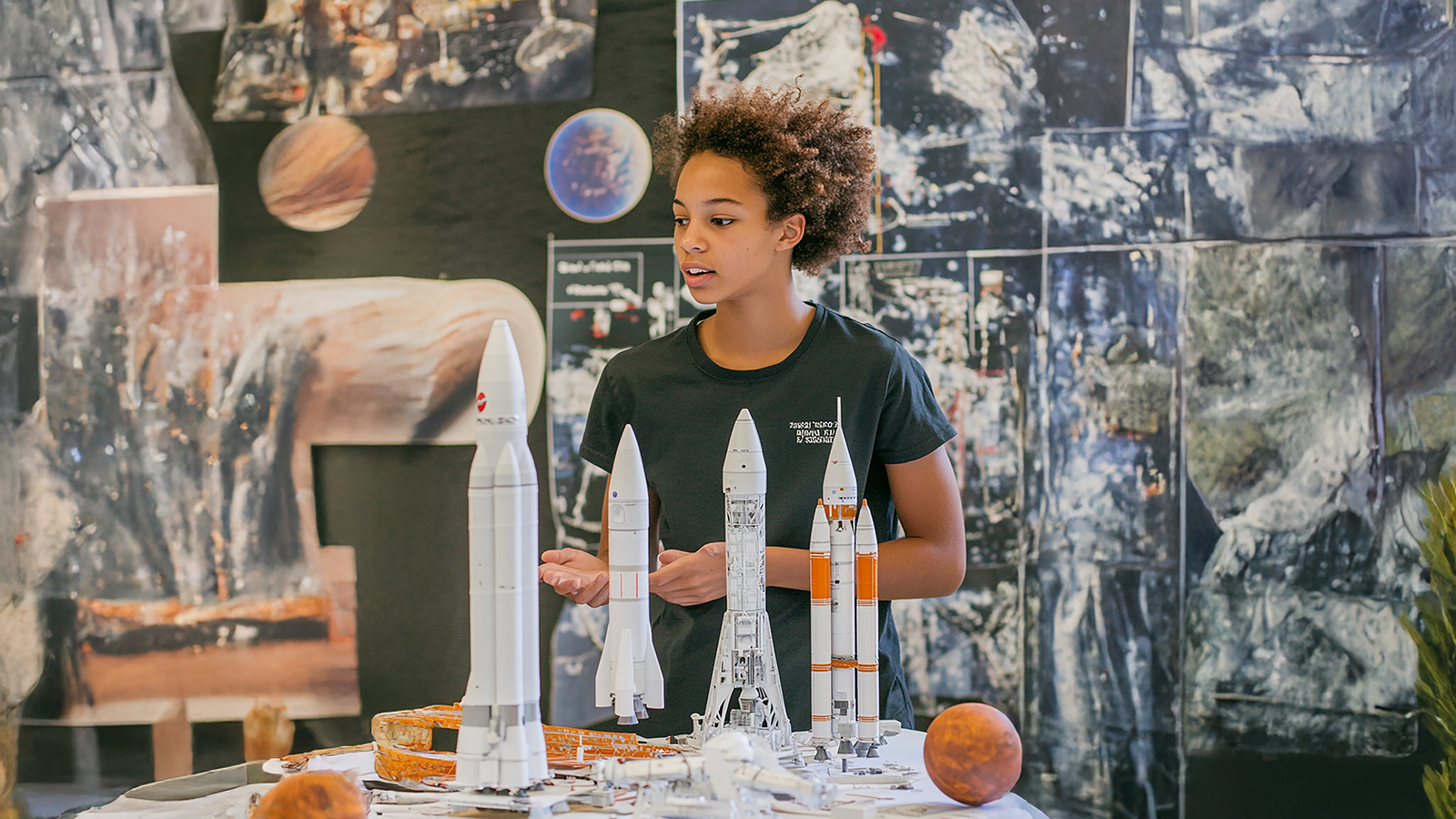 Student in classroom with spaceship figures.