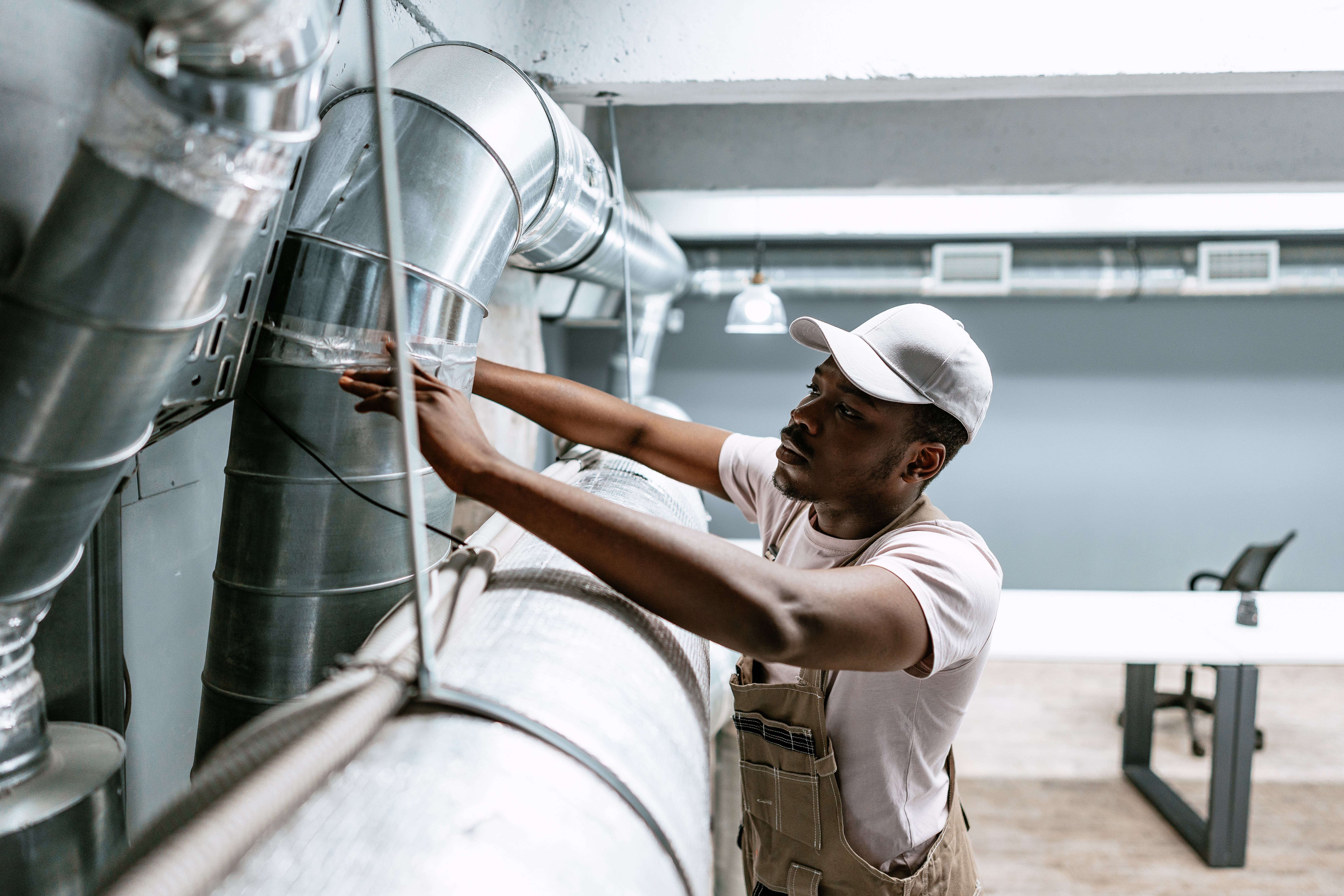 Technician checks and seals metal air ducts in a building.
