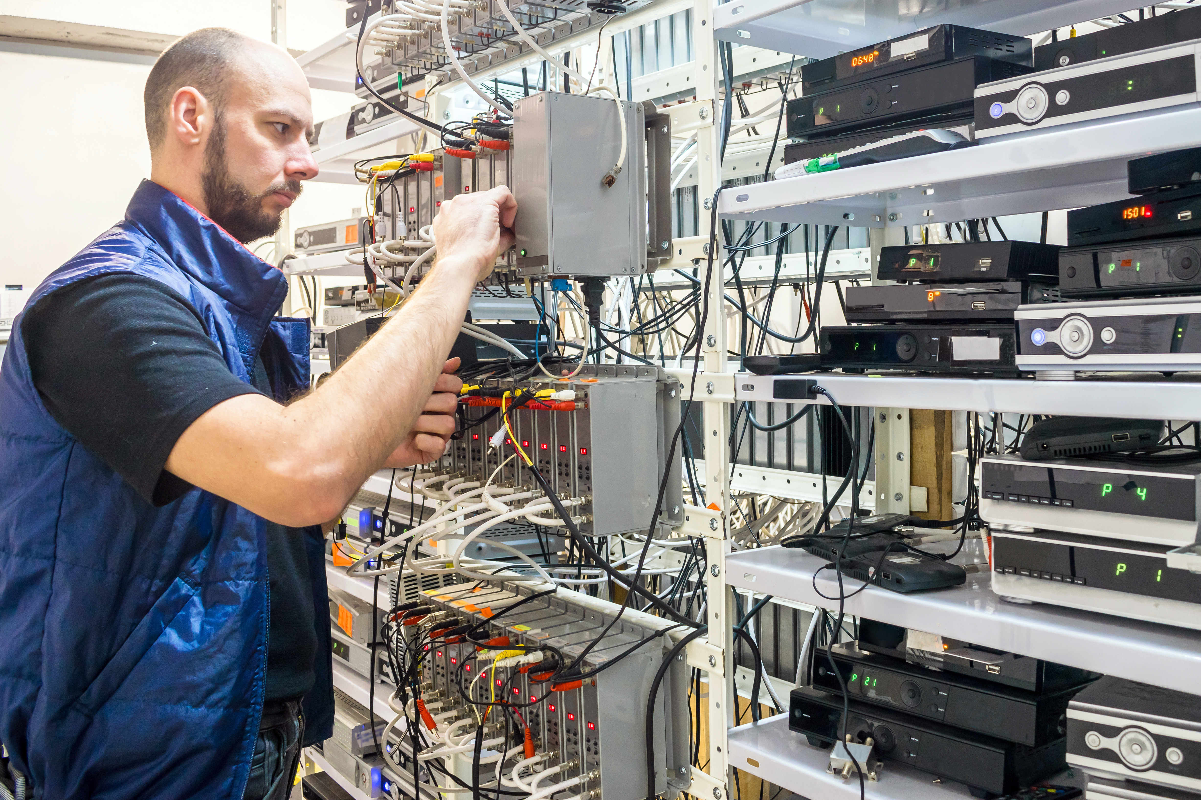 Technician works with wiring and electronic testing equipment on server racks.