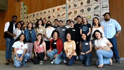 group of students in front of periodic table mural