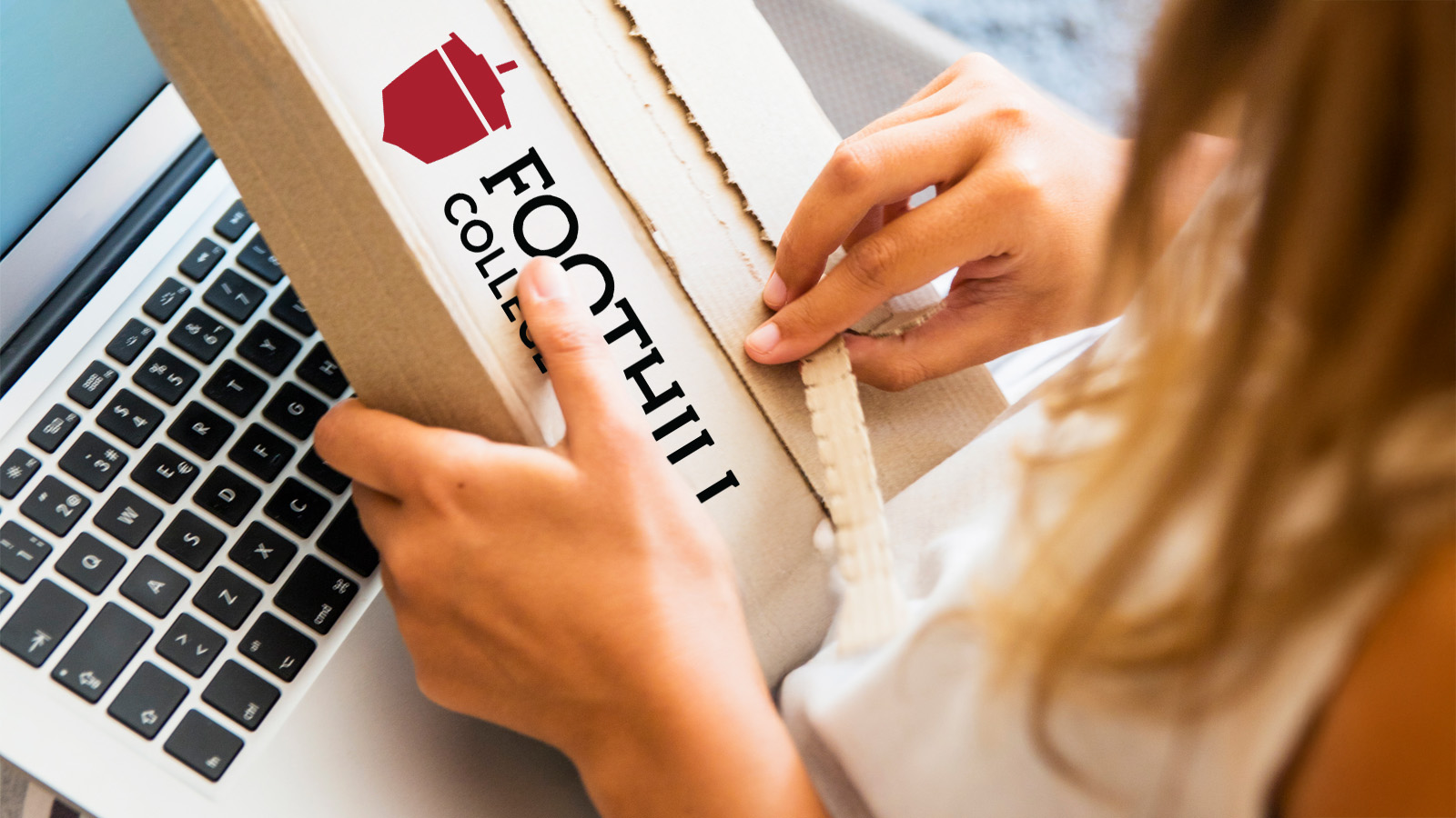 Female hands opening a box with a computer on their lap.