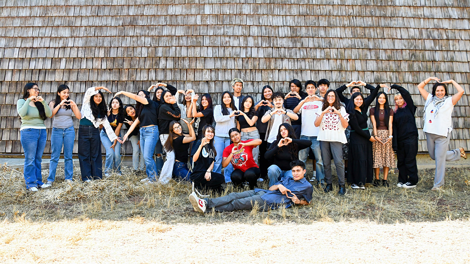 A diverse group of students posing for a photo with natural and fun poses.