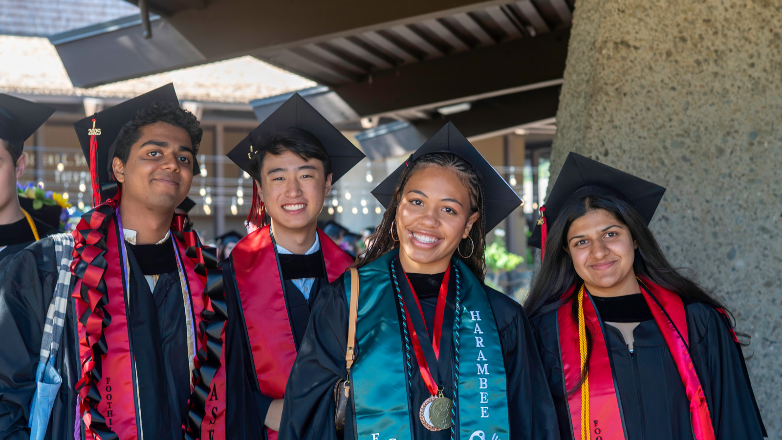 Four Foothill College students during graduation looking and smiling to the camara.