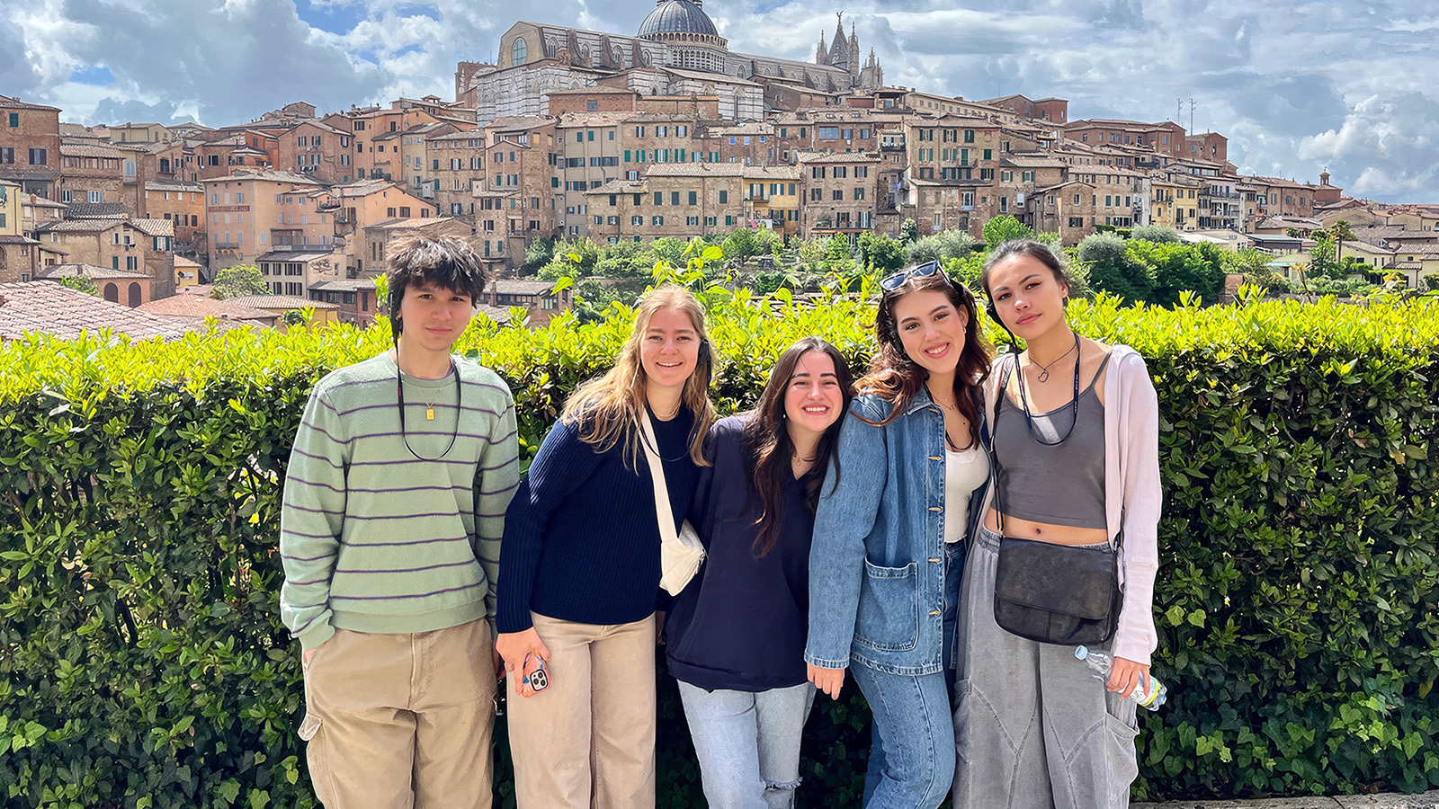 Group of students posing together with a historic European cityscape behind them.