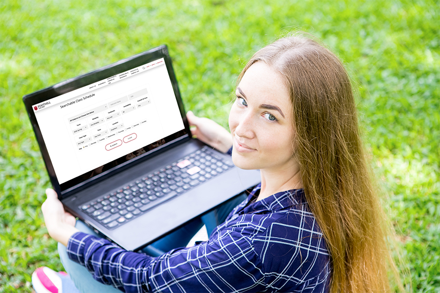 Student searching classes on her computer seated in the grass at Foothill College