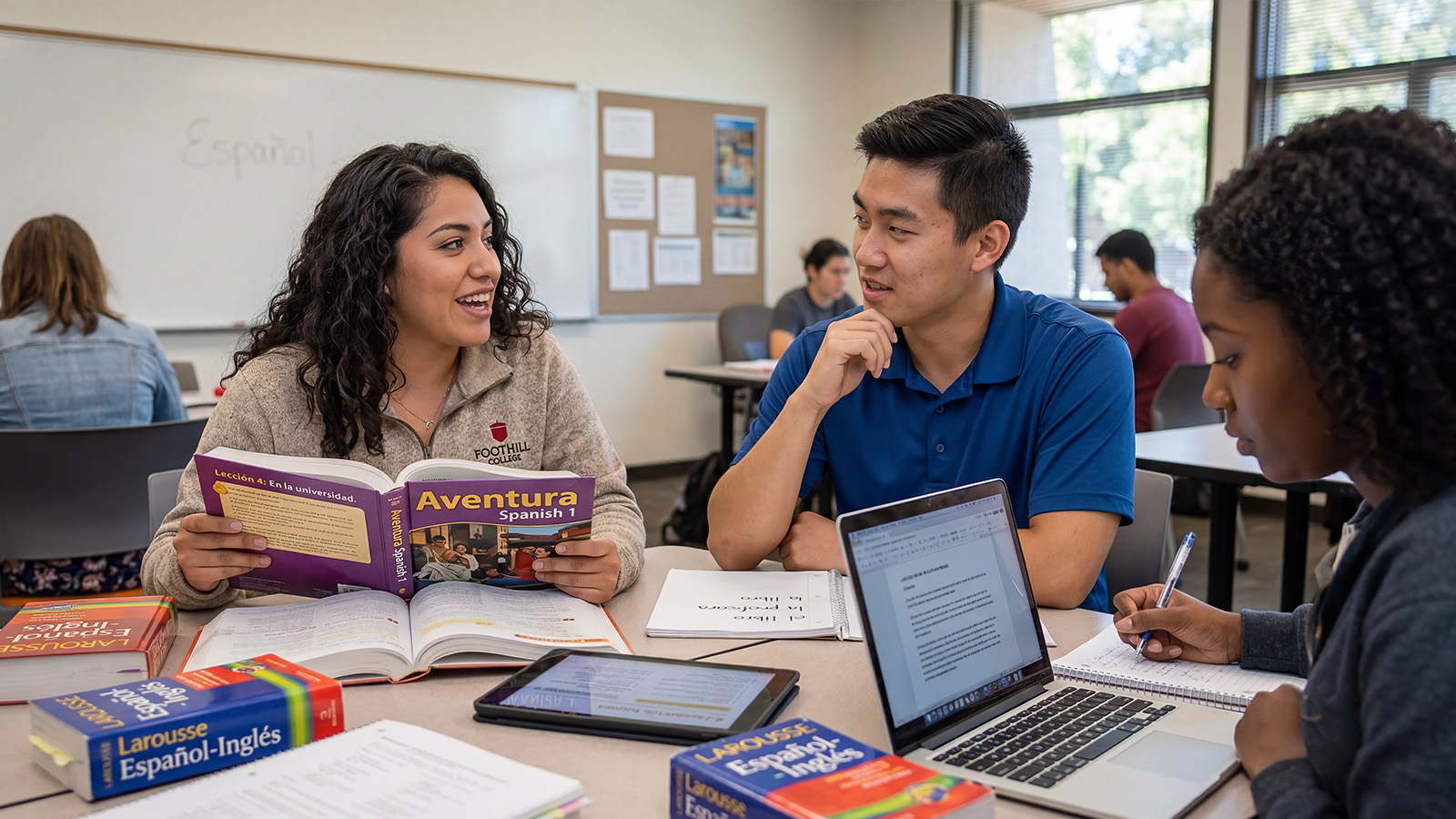 Students practicing Spanish together using textbooks and laptops in a classroom.
